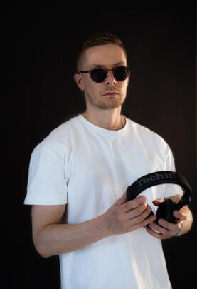 DJ mit Sonnenbrille hält Kopfhörer, Studio/Indoor.