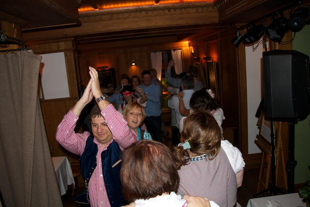 Gäste jubeln und tanzen in rustikaler Location, Nahaufnahme.