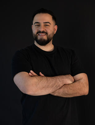 Porträt des DJs mit verschränkten Armen, schwarzer Hintergrund.