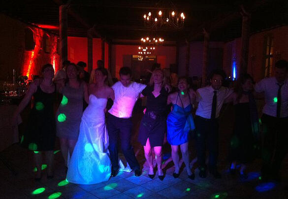 Tanzfläche mit Gästen und buntem Licht in festlicher Location.