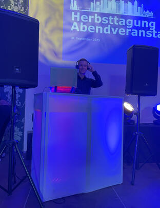 DJ im blauen Licht mischt live am Controller, Seitenansicht.