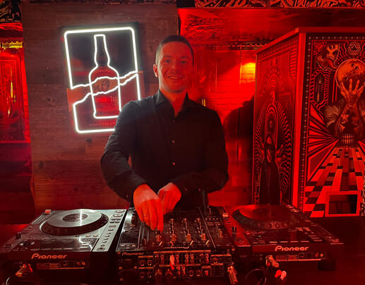 DJ in rotem Neonlicht an Decks – urbaner Clublook.