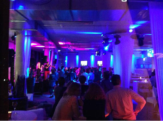 Club/Bar mit violettem Licht, Tanzfläche und DJ-Booth.