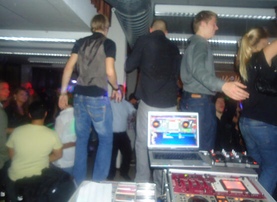 ALT: DJ spielt bei Party mit Gästen am Pult – Interaktion an den Decks.
