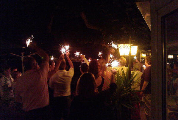 Outdoor-Tanzfläche bei Nacht, Gäste feiern unter Lichterkette.