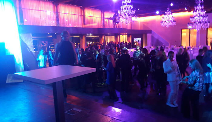 Große Eventhalle mit Bühne, tanzendes Publikum, LED-Wand.